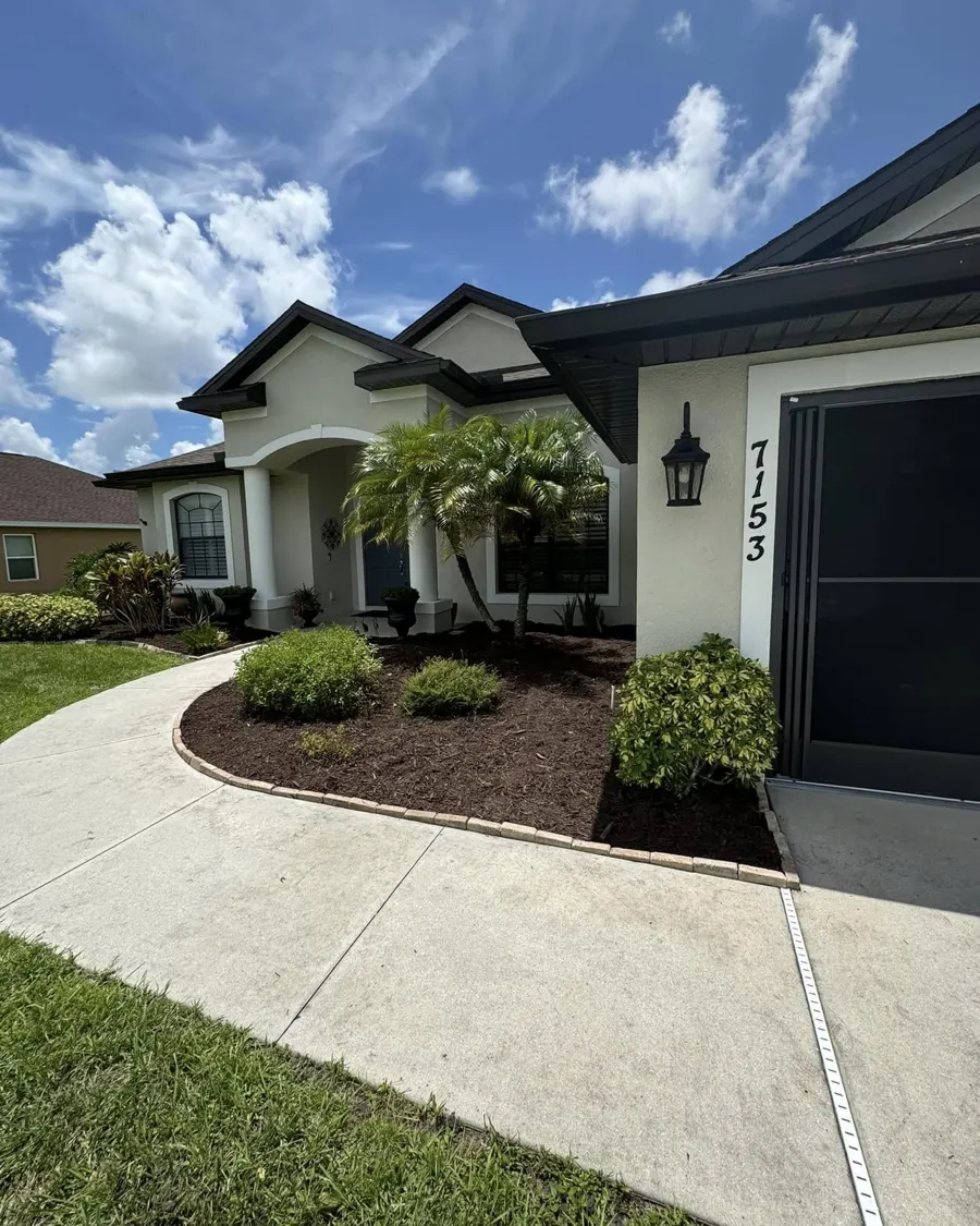 Front yard with fresh mulch beds and a palm
